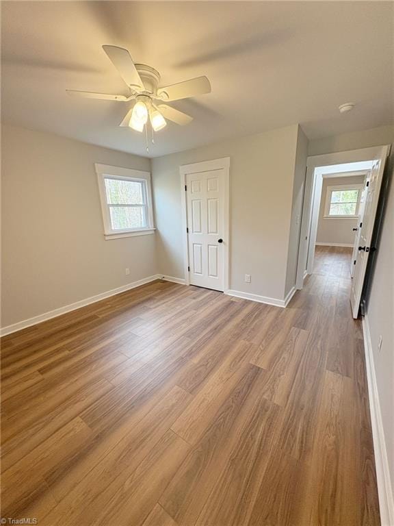 unfurnished bedroom with ceiling fan, wood finished floors, and baseboards