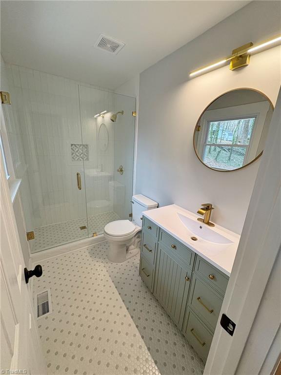 full bath featuring toilet, a stall shower, visible vents, and vanity