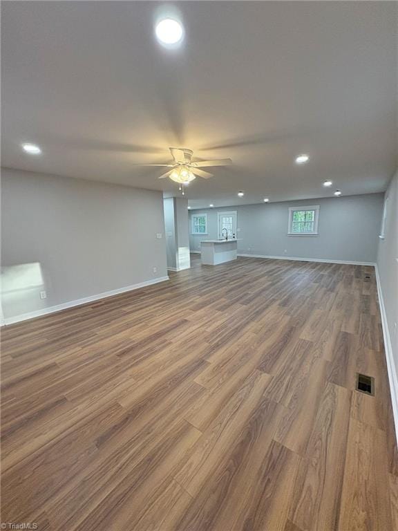 unfurnished living room with baseboards, visible vents, ceiling fan, wood finished floors, and recessed lighting