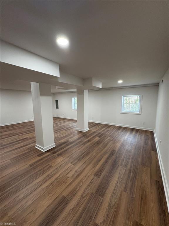 basement featuring plenty of natural light, baseboards, and dark wood-type flooring