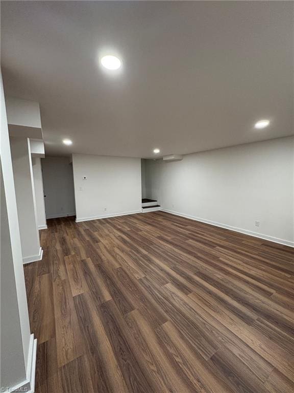 finished below grade area with baseboards, dark wood-type flooring, and recessed lighting