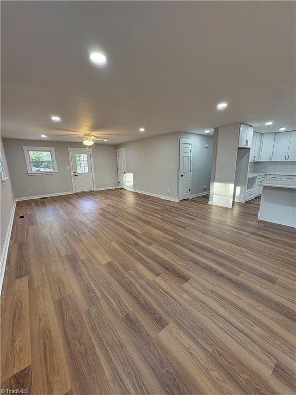 unfurnished living room featuring dark wood-type flooring, recessed lighting, a ceiling fan, and baseboards