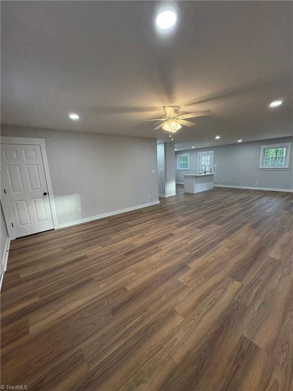 unfurnished living room featuring ceiling fan, dark wood-type flooring, recessed lighting, and baseboards