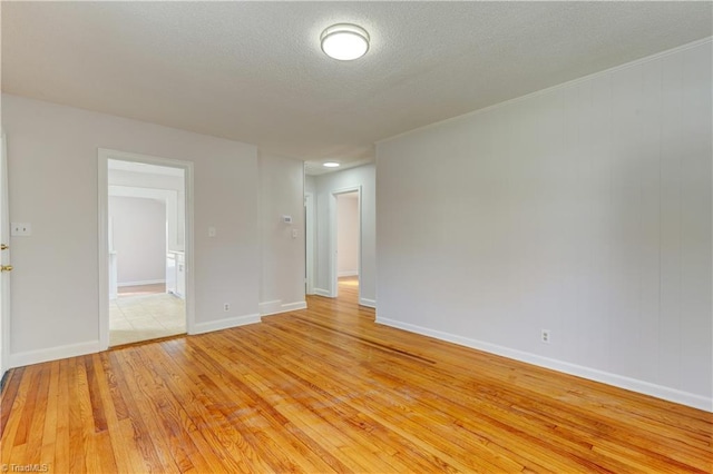 empty room featuring baseboards, a textured ceiling, and light wood finished floors