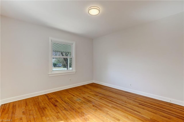 spare room featuring baseboards and light wood finished floors