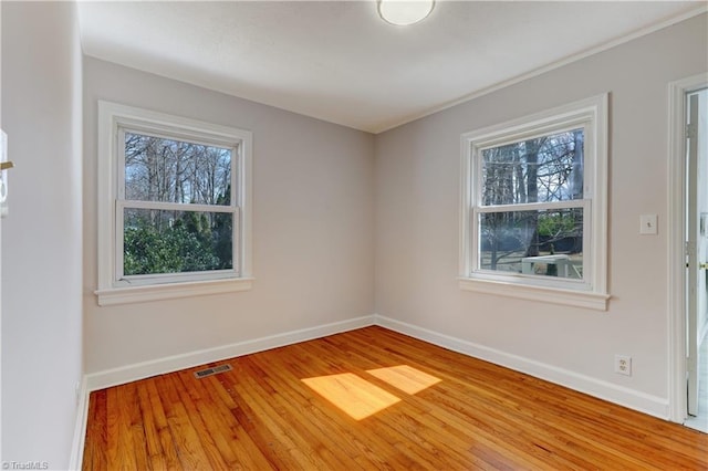 unfurnished room featuring visible vents, baseboards, and wood finished floors