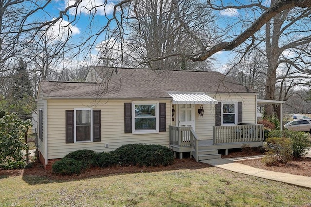 view of front of house with roof with shingles and a front lawn