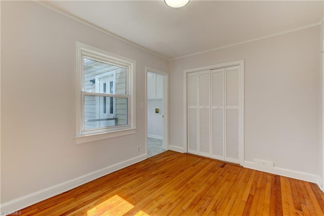 unfurnished bedroom with a closet, baseboards, and light wood-style floors