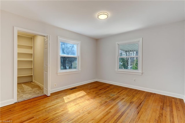 unfurnished bedroom with baseboards, multiple windows, and light wood-style floors