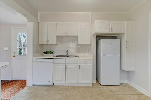 kitchen featuring backsplash, white appliances, light countertops, and a sink