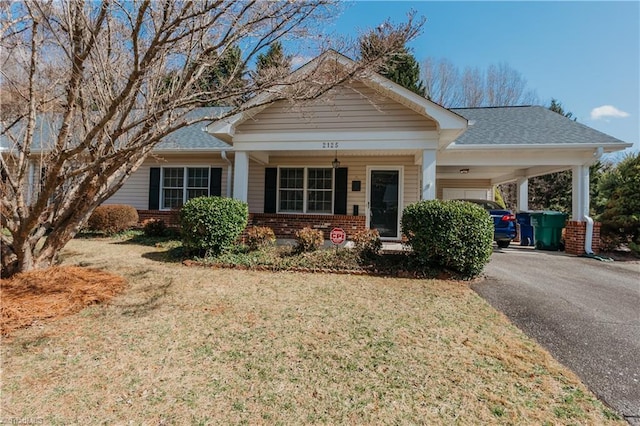 view of front of house featuring a front yard, aphalt driveway, a carport, and brick siding