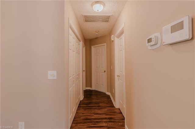 corridor featuring dark wood-style floors, visible vents, and a textured ceiling