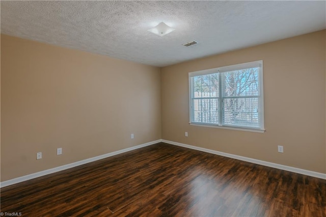 empty room with dark wood-style floors, baseboards, visible vents, and a textured ceiling