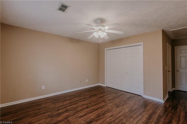 unfurnished bedroom with baseboards, visible vents, a ceiling fan, dark wood finished floors, and a closet