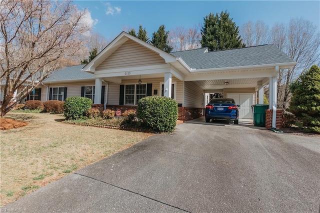 view of front of property with driveway, roof with shingles, a front lawn, a carport, and brick siding