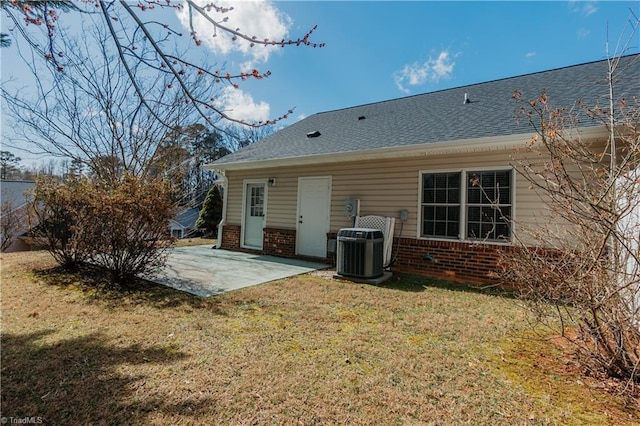 back of house with central air condition unit, a patio area, a lawn, and brick siding