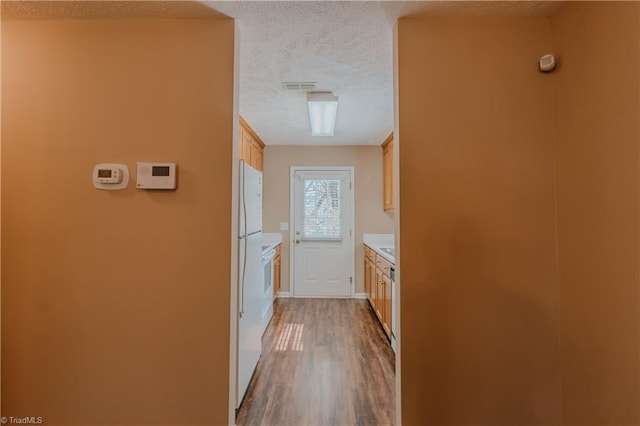 corridor featuring dark wood-style floors, visible vents, and a textured ceiling