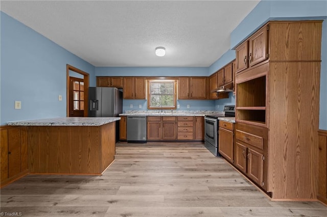 kitchen featuring stainless steel appliances, a textured ceiling, light wood-type flooring, and sink