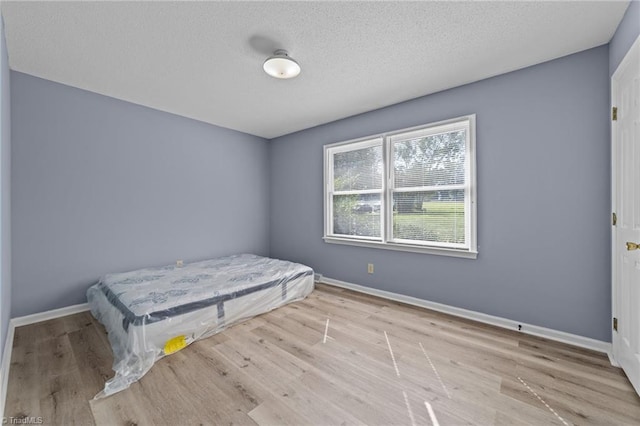 bedroom with light hardwood / wood-style flooring and a textured ceiling