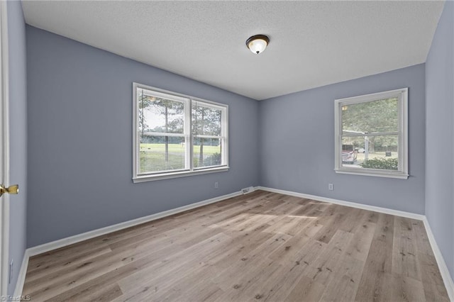 unfurnished room featuring a textured ceiling and light hardwood / wood-style flooring