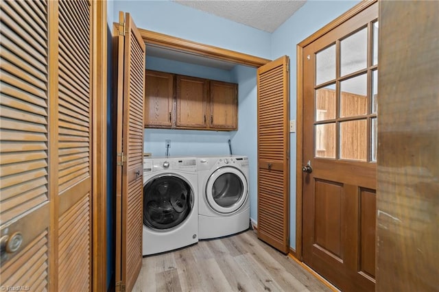 laundry area with separate washer and dryer, cabinets, light wood-type flooring, and a textured ceiling