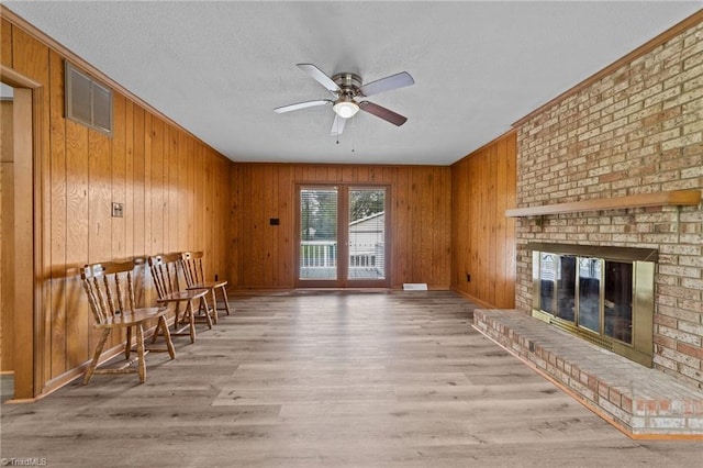 interior space with wood walls, ceiling fan, hardwood / wood-style flooring, and a fireplace