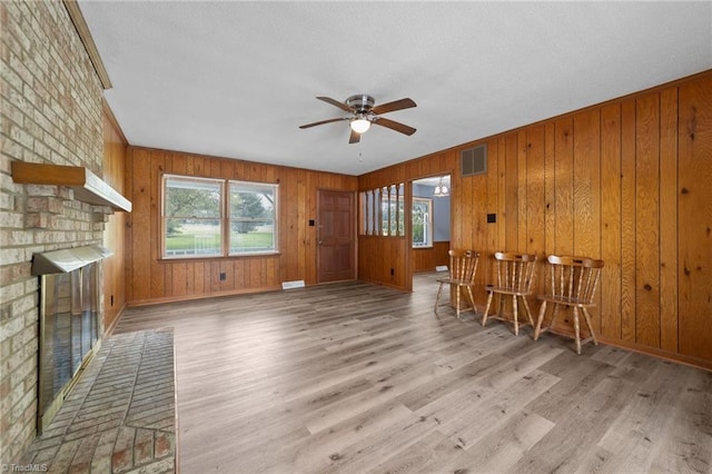 living room with wooden walls, light hardwood / wood-style flooring, and plenty of natural light