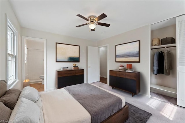 bedroom featuring a closet, connected bathroom, light carpet, and ceiling fan