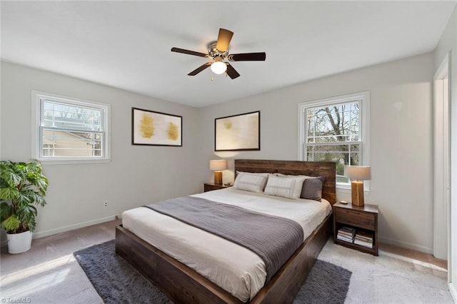 bedroom featuring light colored carpet, ceiling fan, baseboards, and multiple windows