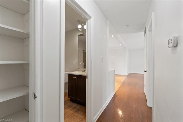 hall featuring a sink, light wood-type flooring, and baseboards