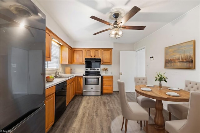 kitchen with black appliances, a ceiling fan, a sink, wood finished floors, and light countertops