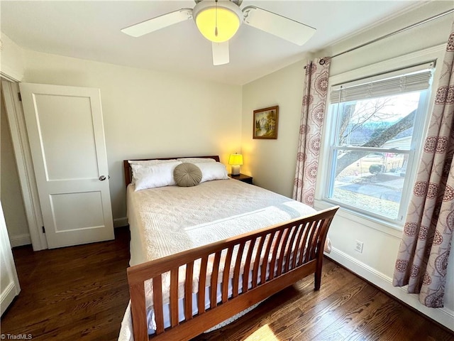 bedroom with dark wood-style flooring, a ceiling fan, and baseboards