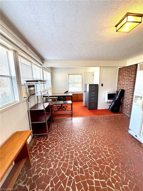 office area featuring heating unit and a textured ceiling