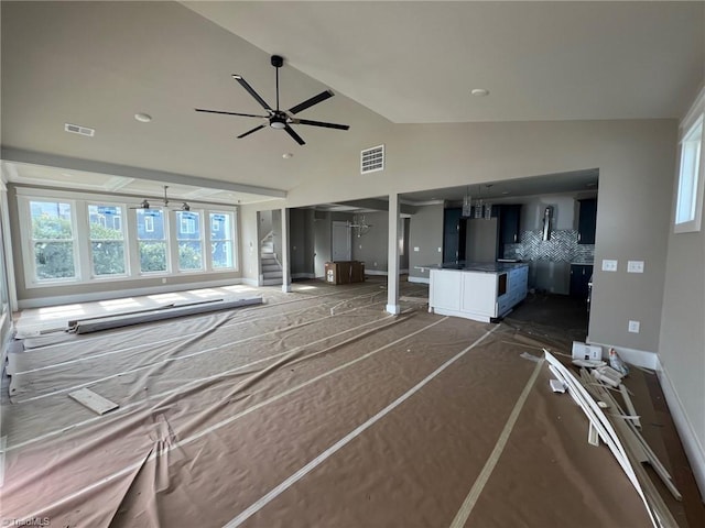 unfurnished living room featuring ceiling fan and vaulted ceiling