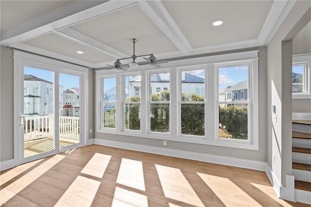 unfurnished sunroom with a healthy amount of sunlight, beamed ceiling, baseboards, and wood finished floors