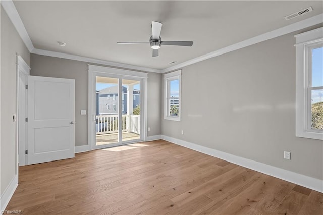 unfurnished room with plenty of natural light, visible vents, crown molding, and wood finished floors