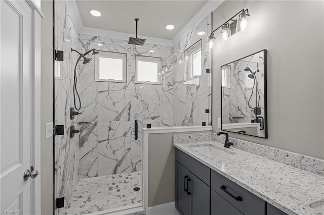full bathroom featuring a marble finish shower and vanity
