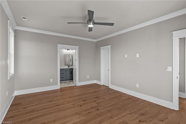 unfurnished bedroom with baseboards, ornamental molding, ensuite bathroom, visible vents, and wood finished floors