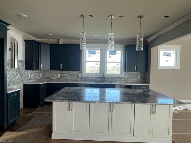 kitchen featuring a center island, stone countertops, tasteful backsplash, and sink