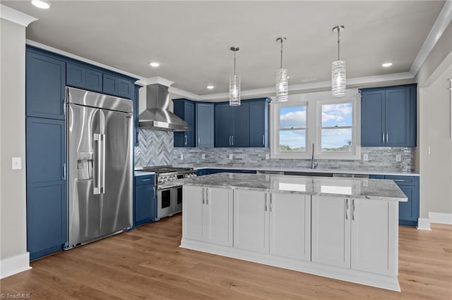 kitchen with a center island, crown molding, high end appliances, wall chimney exhaust hood, and blue cabinets