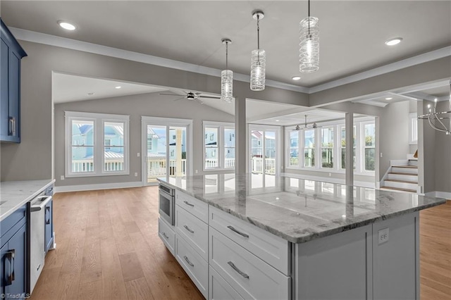 kitchen featuring baseboards, open floor plan, a kitchen island, a healthy amount of sunlight, and light wood finished floors