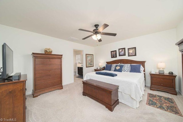 bedroom featuring light colored carpet, baseboards, a ceiling fan, and ensuite bathroom
