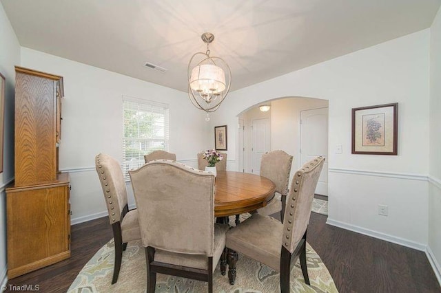 dining area featuring arched walkways, a chandelier, dark wood-style flooring, and baseboards