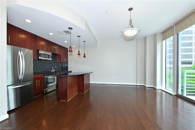 201 N Elm St Unit 310, Greensboro, NC 27401 - kitchen featuring appliances with stainless steel finishes, dark wood-type flooring, tasteful backsplash, a center island, and dark countertops