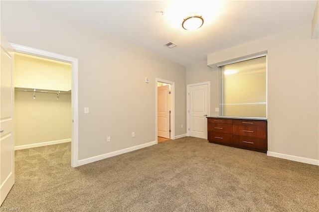 201 N Elm St Unit 310, Greensboro, NC 27401 - unfurnished bedroom with light colored carpet, a walk in closet, a closet, and baseboards