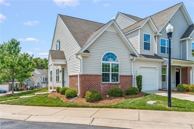 townhome / multi-family property with concrete driveway, a garage, and brick siding