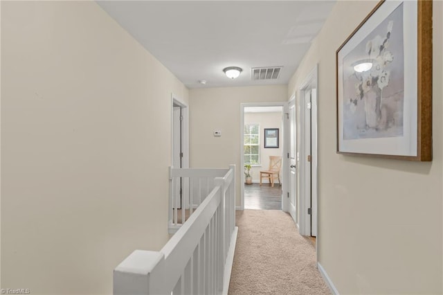hall featuring visible vents, an upstairs landing, baseboards, and carpet floors
