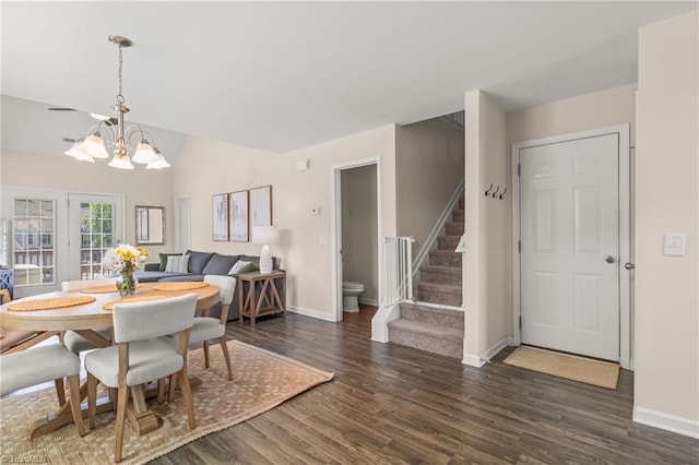 dining area featuring an inviting chandelier, wood finished floors, stairway, baseboards, and lofted ceiling
