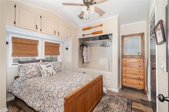 bedroom featuring dark wood-style floors, crown molding, baseboards, vaulted ceiling, and a closet