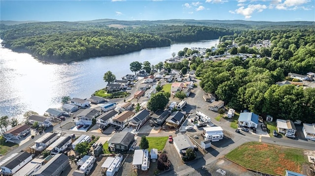 view of property location with a forest, a large body of water, and nearby suburban area